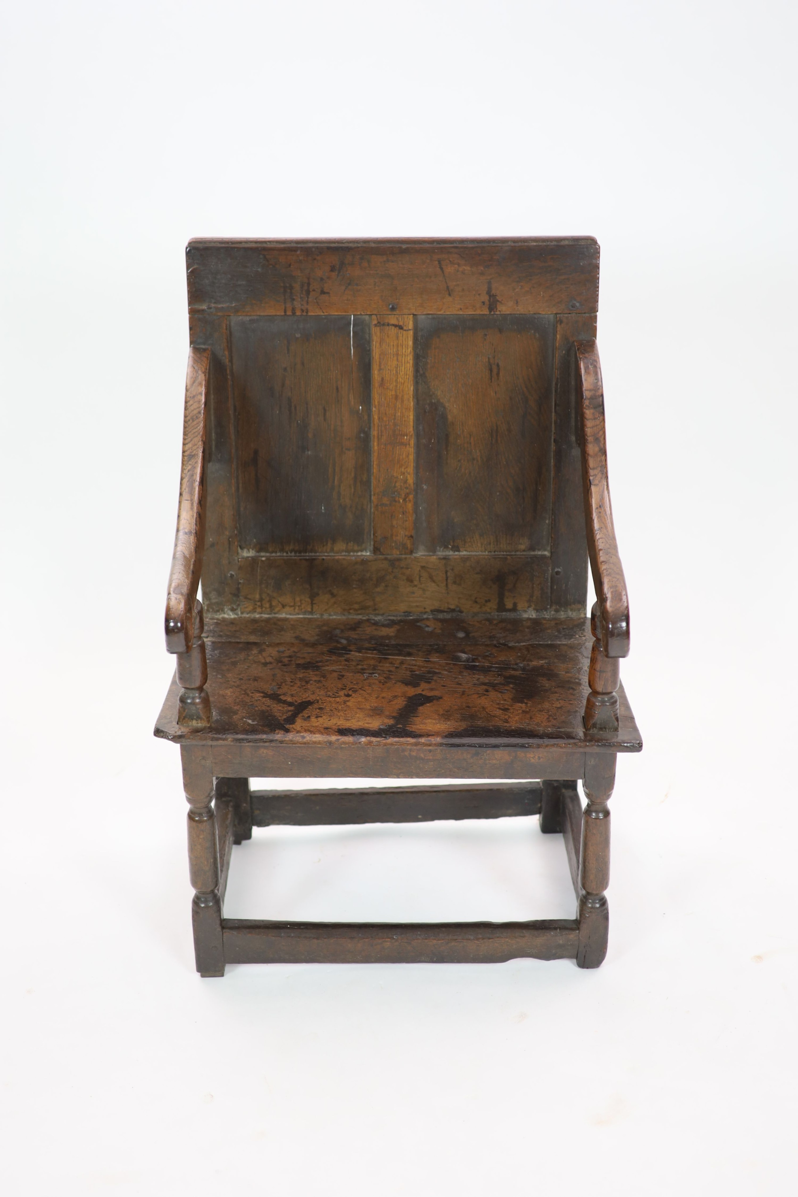 A 17th century panelled oak open armchair, the seat initialled 'PO' H 97cm. W 66cm. D 52cm.